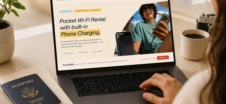 A desk with a laptop and passport showing the Noomi pocket Wi-Fi rental with built-in phone charging